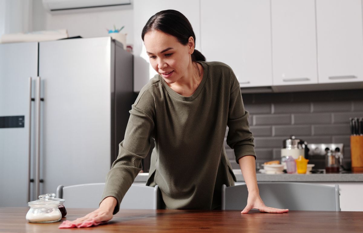 Wiping a kitchen table with a cloth